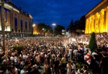 ილუსტრაცია, რომელიც გამოხატავს AI-ის, Gen Z-ისა და საქართველოს მომავლის პარტნიორობას. გამოსახულებაზე ნაჩვენებია ახალგაზრდა თაობა, რომელიც სიმბოლურად Gen Z-ს წარმოადგენს და დგას თავდაჯერებით, თანამედროვე ტექნოლოგიებთან ერთად, რაც სიქველესა და პოზიტიური ცვლილებების მისწრაფებას გამოხატავს. ფონზე ჩანს ტრადიციული პოლიტიკური ფიგურები, რომლებიც მშვიდობიანი ლიდერობის გადაცემის სიმბოლოა. ნათელი და მზიანი თბილისის სკაილაინი ოპტიმიზმსა და მომავლის იმედს უსვამს ხაზს.